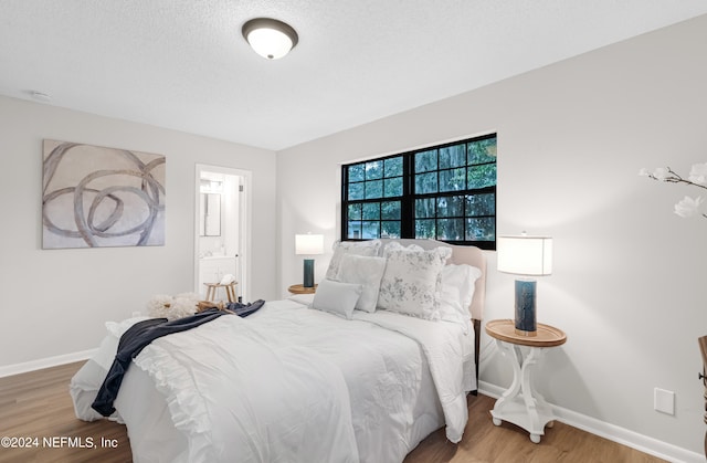 bedroom with a textured ceiling, connected bathroom, and hardwood / wood-style flooring