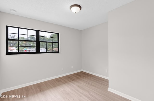 spare room with light wood-type flooring and a textured ceiling