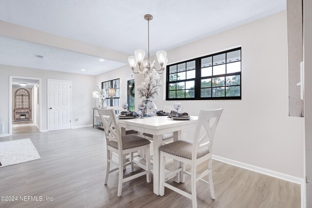 dining room with a textured ceiling, light hardwood / wood-style flooring, and a notable chandelier