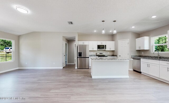 kitchen with a center island, sink, light hardwood / wood-style flooring, appliances with stainless steel finishes, and decorative light fixtures