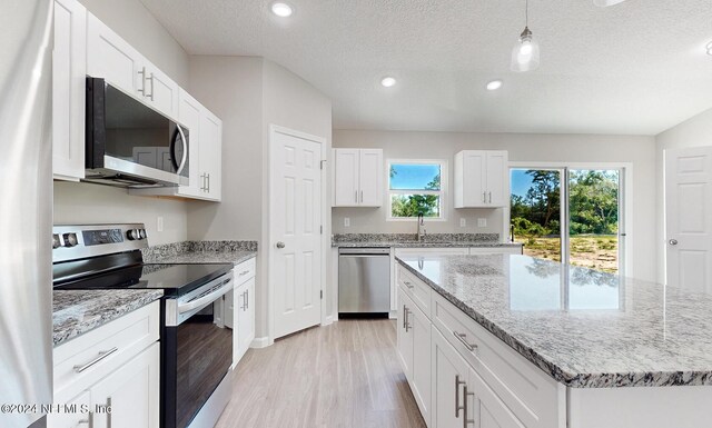 kitchen with light stone counters, light hardwood / wood-style floors, appliances with stainless steel finishes, and a kitchen island