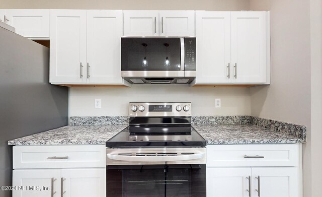 kitchen featuring light stone countertops, stainless steel appliances, and white cabinetry