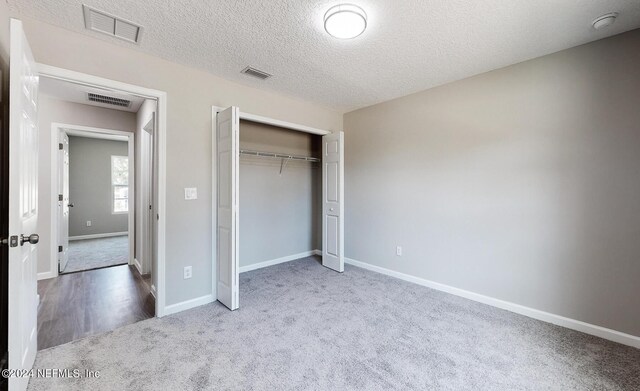 unfurnished bedroom featuring a closet, light colored carpet, and a textured ceiling