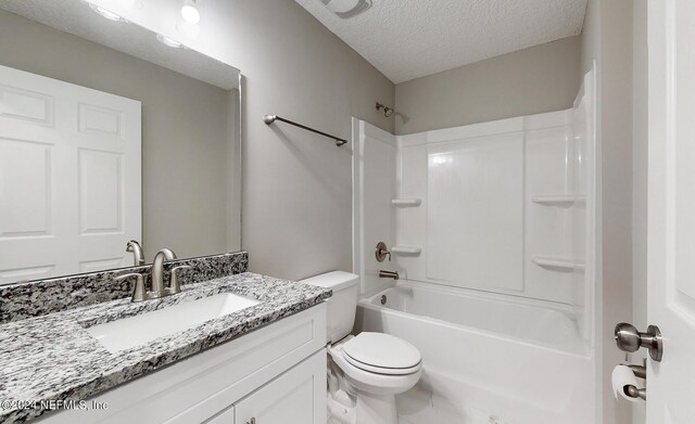 full bathroom with a textured ceiling, bathing tub / shower combination, vanity, and toilet