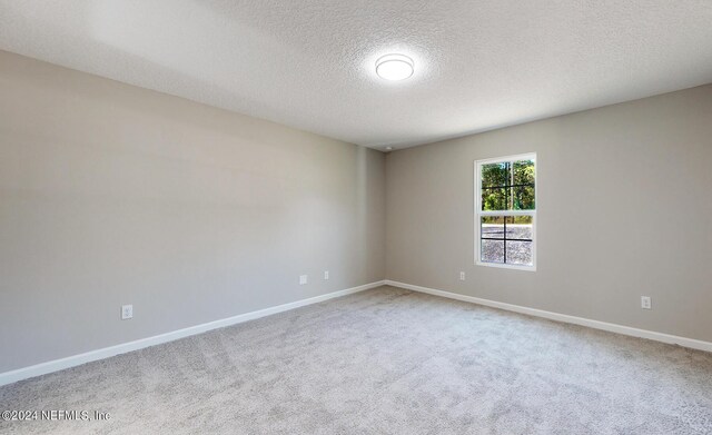 carpeted empty room featuring a textured ceiling