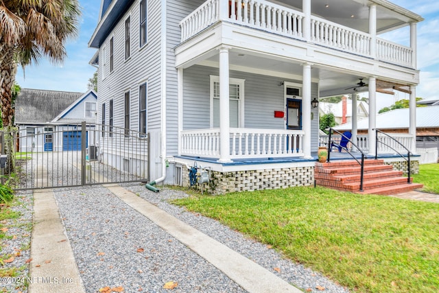 view of front of house with ceiling fan, a porch, a balcony, and a front yard