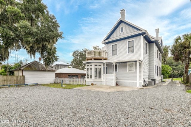 rear view of house featuring cooling unit, a balcony, and a patio