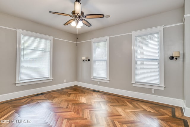 unfurnished room featuring ceiling fan, plenty of natural light, and parquet flooring