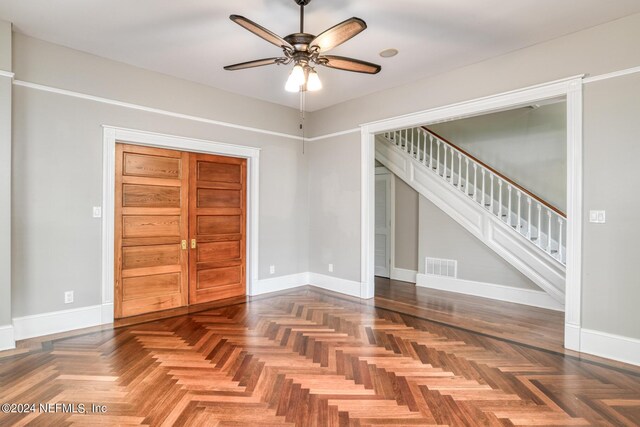 interior space with dark parquet flooring and ceiling fan