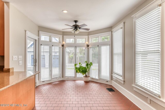 unfurnished sunroom featuring ceiling fan