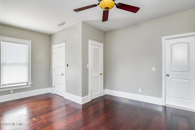 unfurnished bedroom with multiple windows, dark hardwood / wood-style floors, and ceiling fan