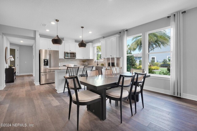 dining space with a wealth of natural light, dark hardwood / wood-style floors, and a textured ceiling