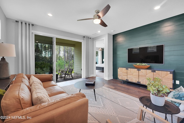 living room featuring hardwood / wood-style floors, ceiling fan, and wooden walls