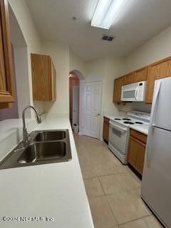 kitchen with light tile patterned floors, white appliances, and sink