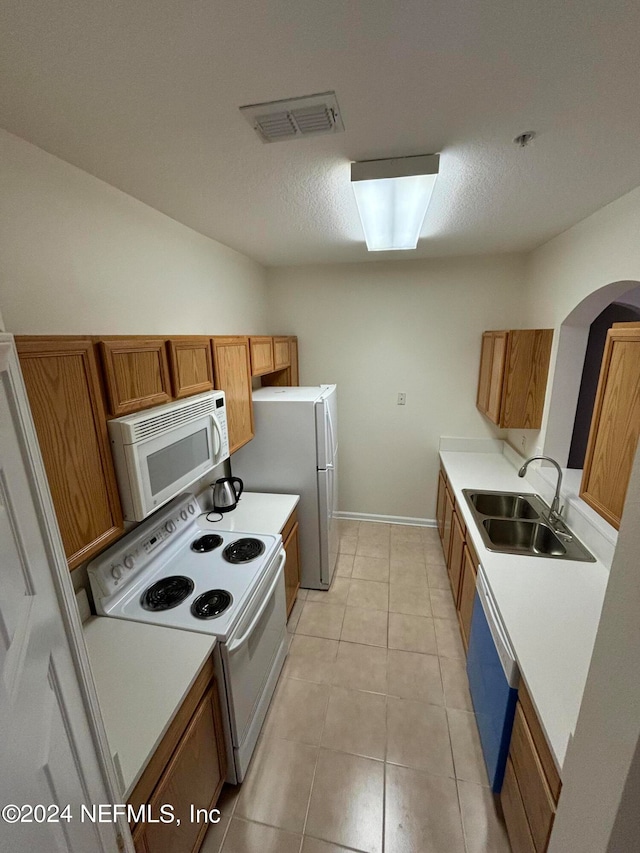 kitchen featuring light tile patterned floors, white appliances, sink, and a textured ceiling