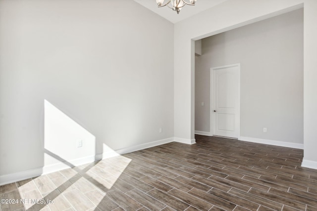 spare room featuring dark hardwood / wood-style floors and an inviting chandelier