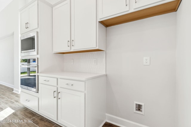 kitchen featuring backsplash, white cabinetry, and appliances with stainless steel finishes