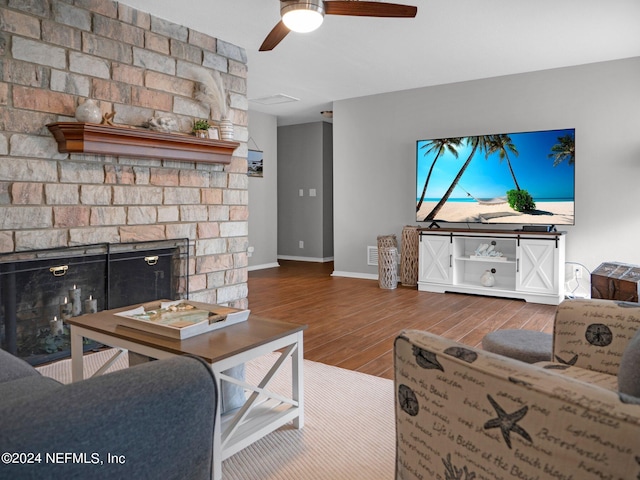 living room with wood-type flooring, ceiling fan, and a fireplace