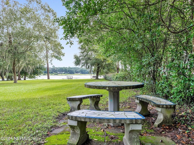 surrounding community with a water view and a yard