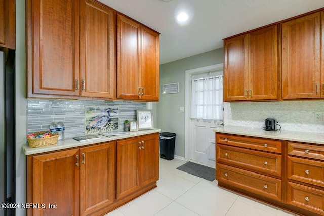 kitchen featuring decorative backsplash, light stone countertops, and light tile patterned floors