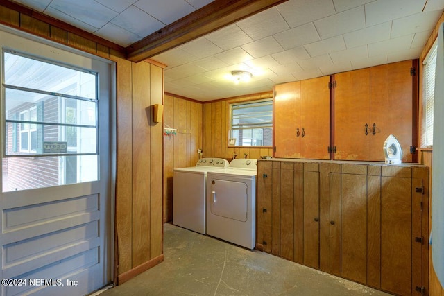 laundry area with separate washer and dryer and wood walls