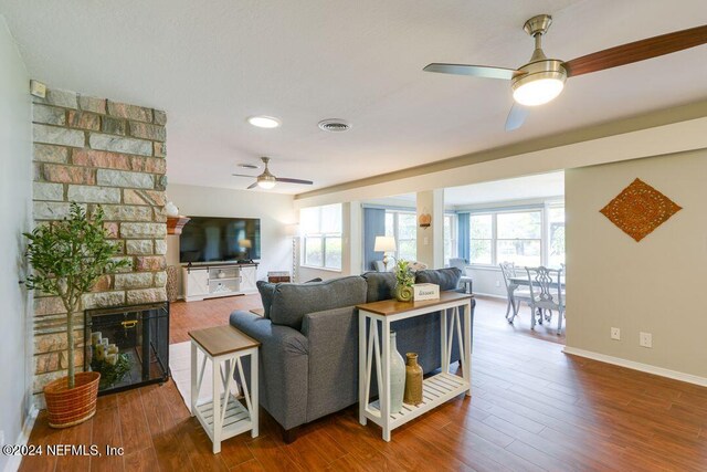 living room with ceiling fan, hardwood / wood-style flooring, and a fireplace