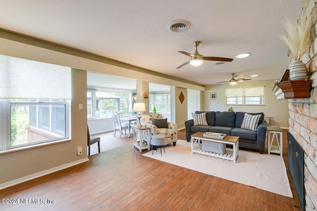 living room featuring a fireplace, hardwood / wood-style floors, and ceiling fan