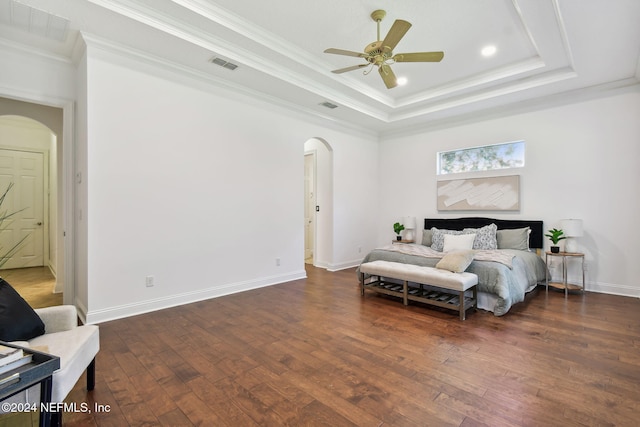 bedroom featuring a raised ceiling, ceiling fan, dark wood-type flooring, and ornamental molding