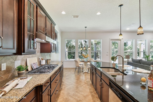 kitchen featuring sink, tasteful backsplash, dark stone counters, pendant lighting, and appliances with stainless steel finishes