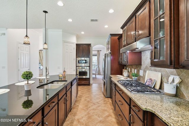 kitchen with sink, stainless steel appliances, backsplash, dark stone countertops, and decorative light fixtures