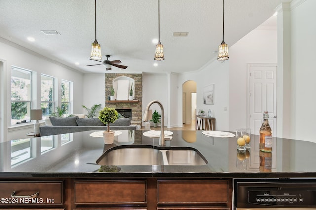 kitchen featuring crown molding, sink, decorative light fixtures, a fireplace, and black dishwasher