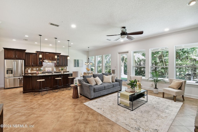 living room with ceiling fan, sink, light tile patterned floors, and a textured ceiling