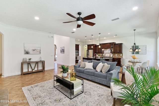 living room with ceiling fan with notable chandelier, crown molding, and a textured ceiling