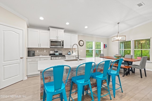 kitchen with light wood-type flooring, sink, appliances with stainless steel finishes, and white cabinets