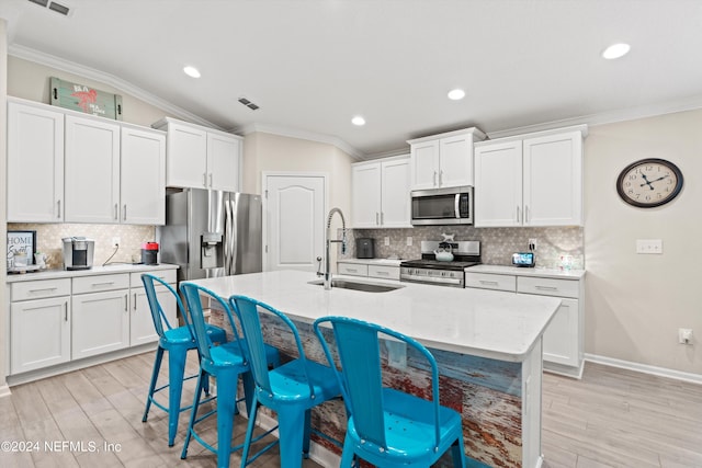 kitchen featuring stainless steel appliances, a center island with sink, white cabinetry, and sink