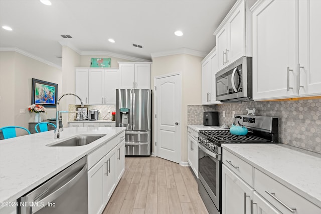 kitchen featuring light stone countertops, light hardwood / wood-style flooring, appliances with stainless steel finishes, sink, and white cabinetry