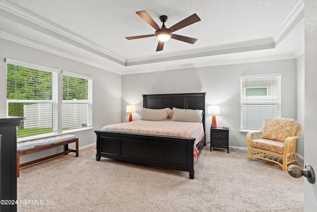 carpeted bedroom featuring multiple windows, ceiling fan, a tray ceiling, and crown molding