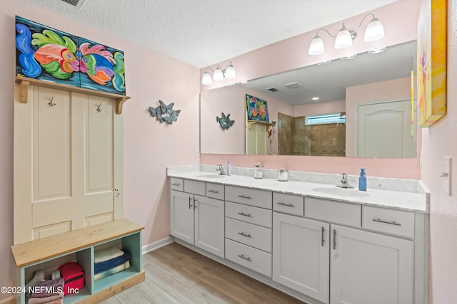 bathroom with vanity, a textured ceiling, wood-type flooring, and a shower with shower door