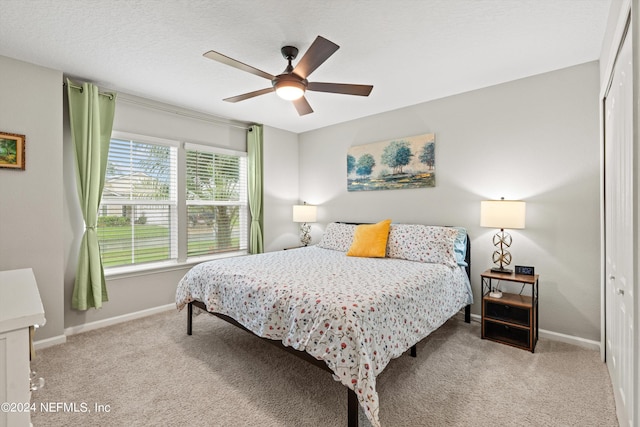 bedroom featuring a closet, ceiling fan, light colored carpet, and a textured ceiling