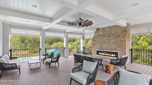 wooden deck featuring ceiling fan and an outdoor living space with a fireplace