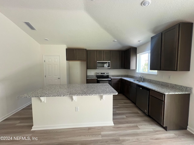 kitchen with sink, appliances with stainless steel finishes, light hardwood / wood-style floors, and a kitchen island