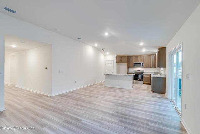 kitchen featuring lofted ceiling, sink, a center island, appliances with stainless steel finishes, and light hardwood / wood-style floors