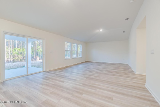 empty room featuring vaulted ceiling and light hardwood / wood-style floors