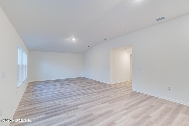 unfurnished room featuring lofted ceiling and light hardwood / wood-style flooring