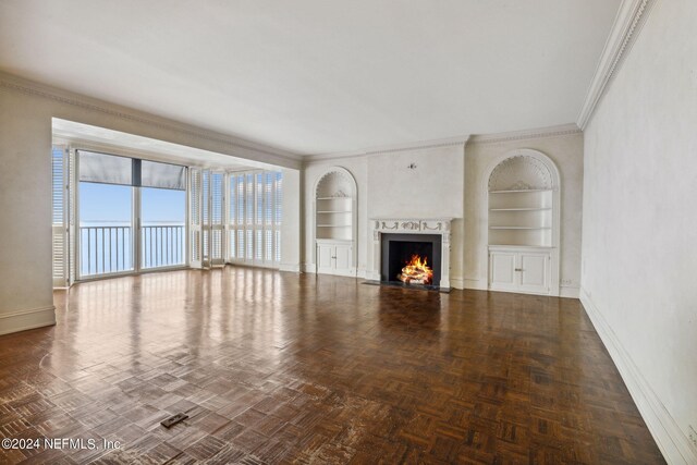 unfurnished living room featuring built in shelves, dark parquet flooring, and ornamental molding