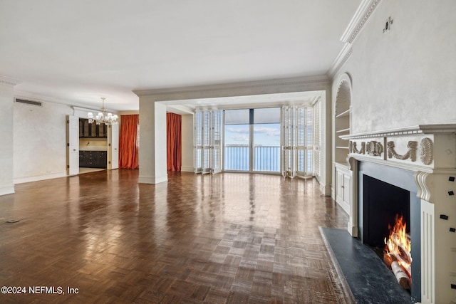 unfurnished living room with built in shelves, ornamental molding, and an inviting chandelier