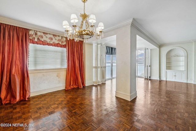 spare room featuring built in shelves, dark parquet flooring, a notable chandelier, and ornamental molding