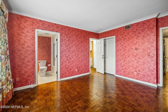 unfurnished bedroom featuring dark parquet flooring, crown molding, and ensuite bath