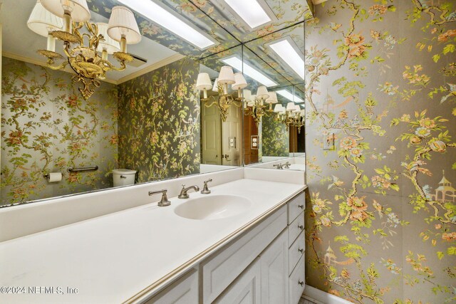 bathroom with toilet, ornamental molding, and vanity