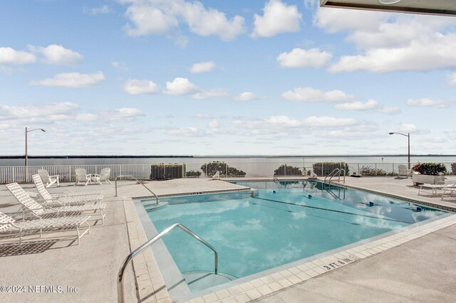 view of pool featuring a water view and a patio